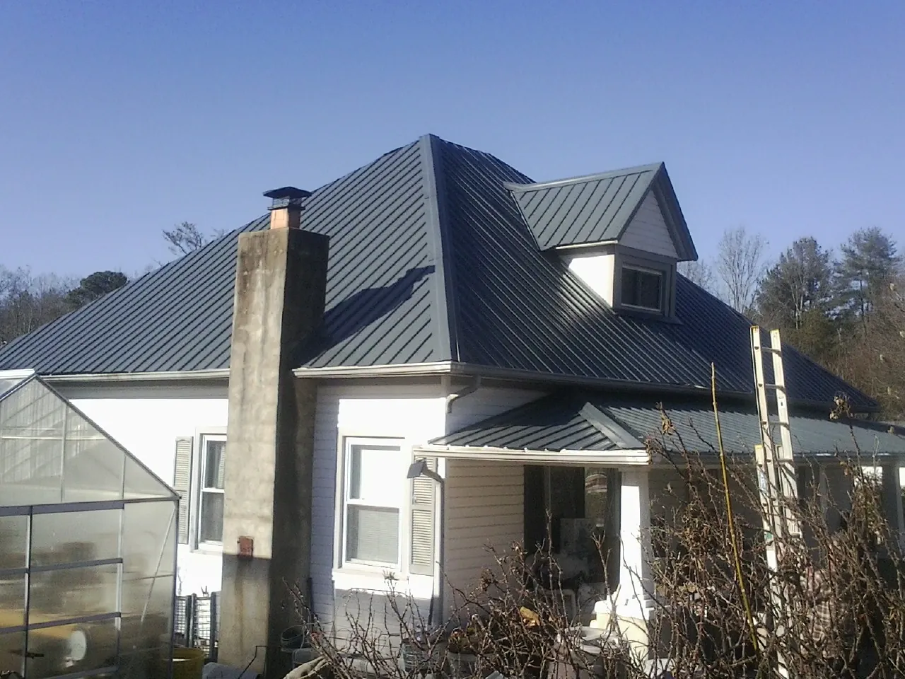 Dark blue standing seam metal roof on a white farmhouse with dormer — Slate & Tile Roof Repair by Roofing Brothers in Bensalem