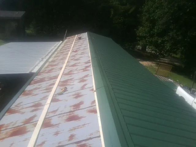 Old rusted panels beside newly installed green metal roofing — Wind Damage Roof Repair by Roofing Brothers in Bensalem