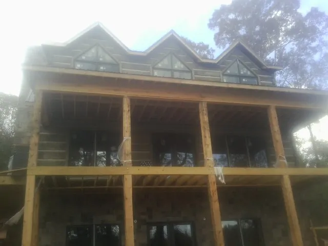 Dormers and porch framing on a large log home under construction — Roof Coating work by our crew in Bensalem