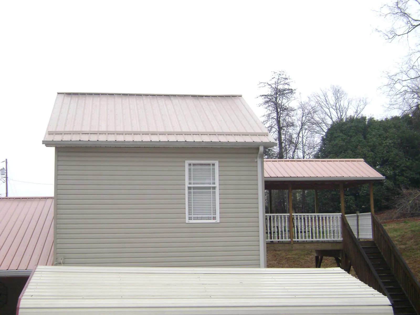 Tan metal roofs on a two story addition and attached porch, from a Roof Replacement job in Bensalem