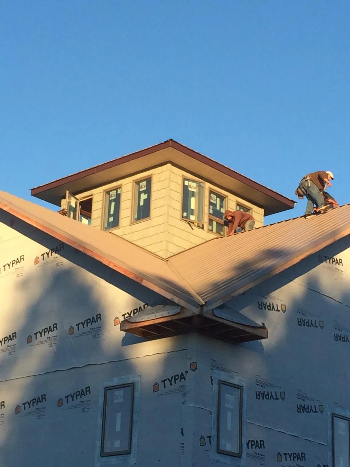 Roofers working around a rooftop cupola on a new metal roof at sunset — Roof Waterproofing in Bensalem by Roofing Brothers